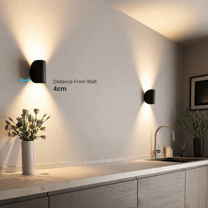 Applique noire sur un mur de cuisine, avec une flèche indiquant sa distance au mur, éclairage chaud vers le haut et le bas. 14