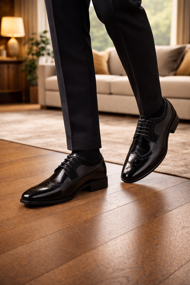 Homme en mouvement en pantalon noir portant les chaussures en cuir noir verni à perforations, sur un parquet de salon. 2