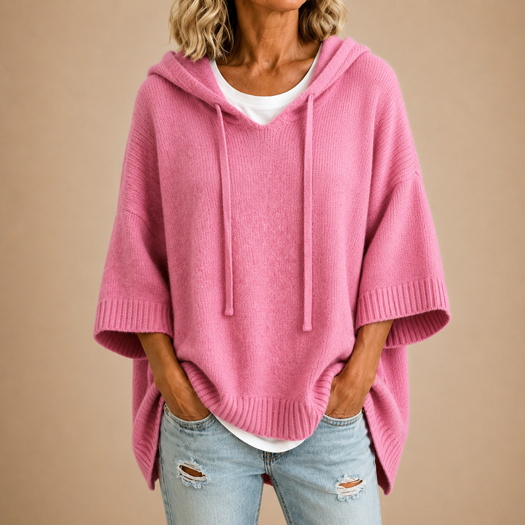Poncho rose en maille à capuche et manches trois-quarts, porté sur un t-shirt blanc et un jean clair déchiré. 8
