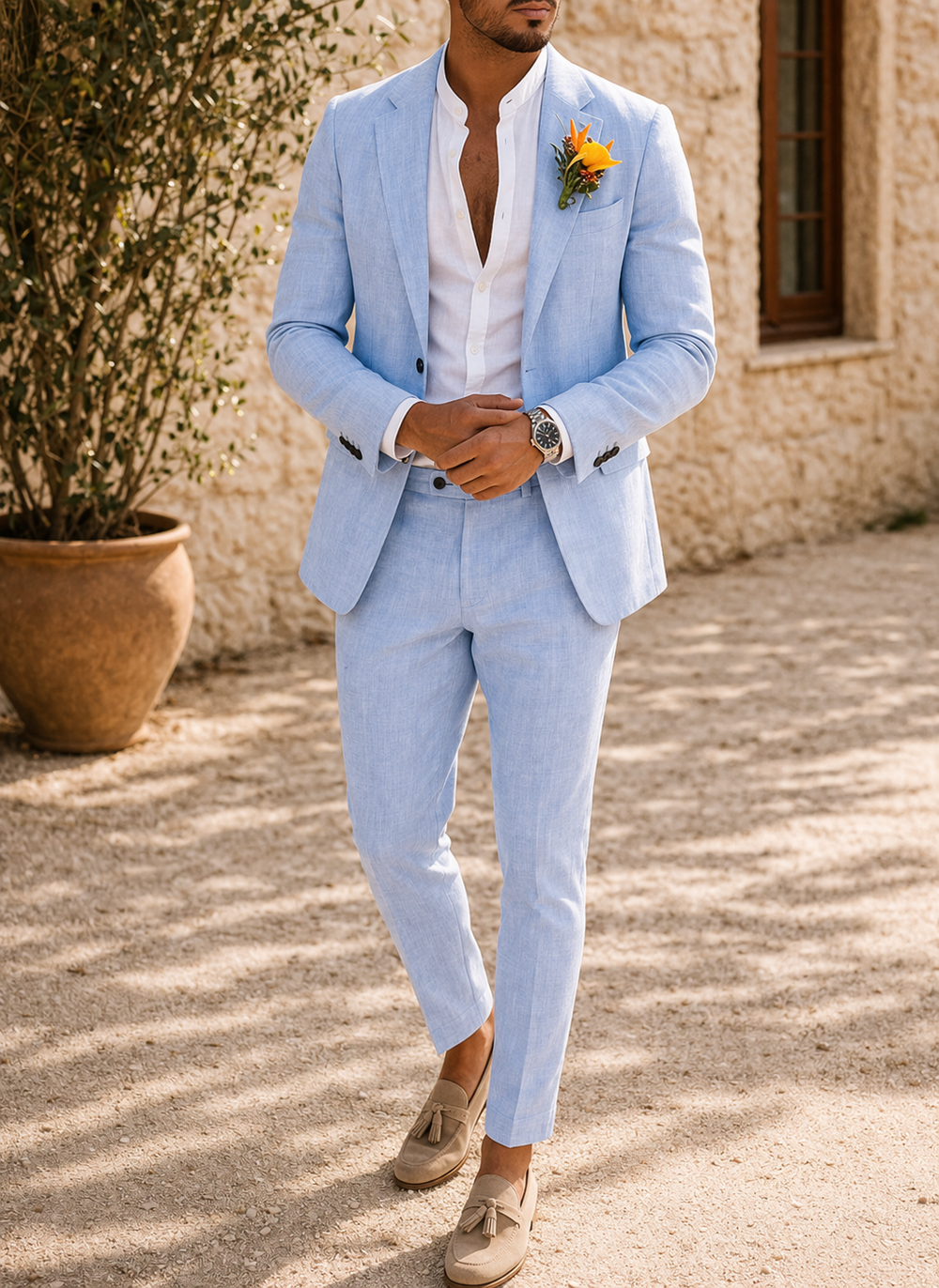 Version bleu ciel du costume porté par un homme, mains jointes devant lui, montre au poignet, boutonnière orange et mocassins beiges. 2