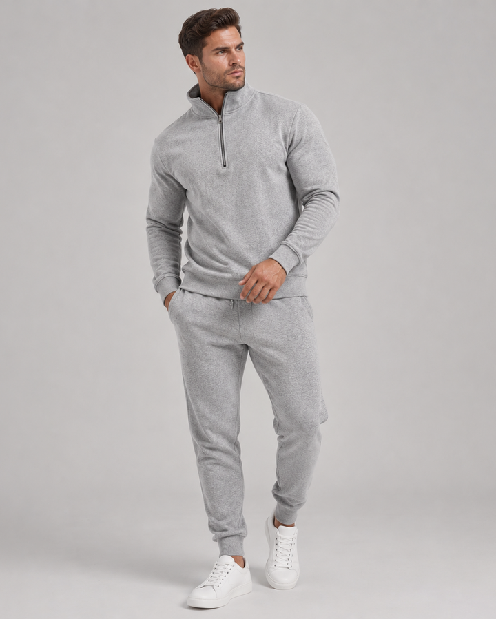 Homme en pied portant l'ensemble gris chiné à col zippé, mains en poche, baskets blanches 1