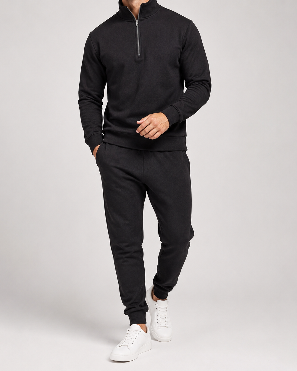Homme portant l'ensemble noir à demi-zip avec jogging à bas élastiqués, marchant en baskets blanches 3