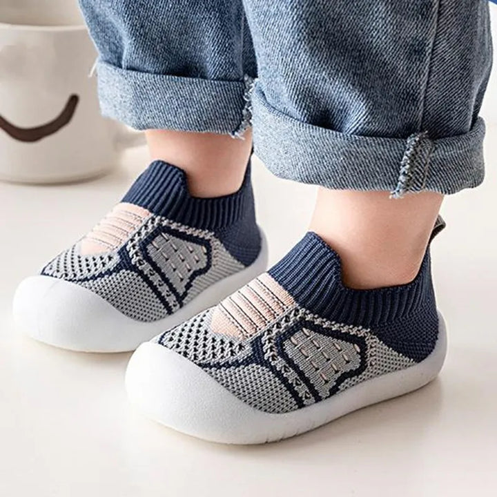 Gros plan sur des chaussures en maille bleu marine et grise à rayures beiges, portées avec un jean retroussé. 14