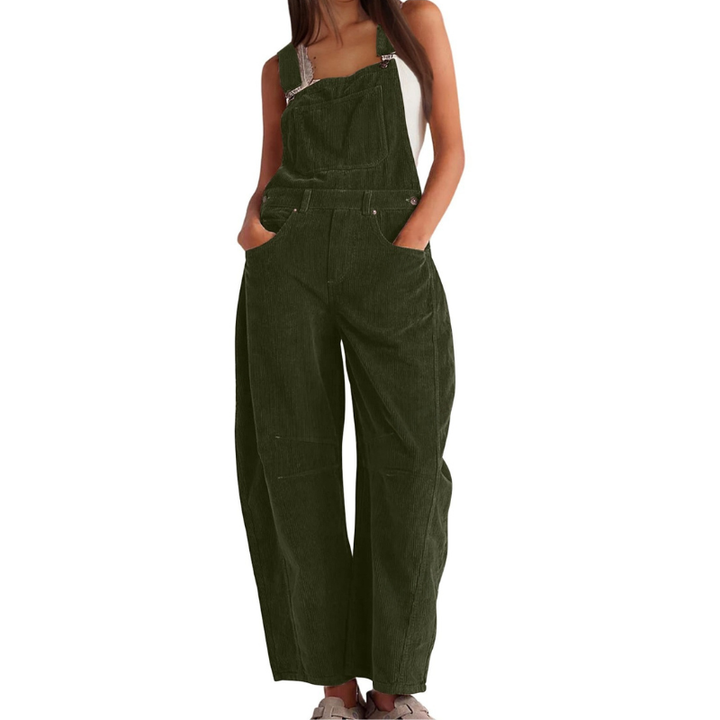 Salopette en velours côtelé vert kaki portée de face par une femme, mains dans les poches, jambes larges et bretelles à boucles. 6