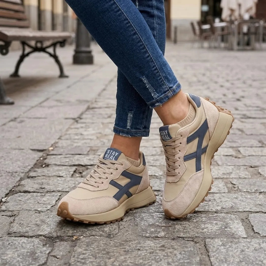 Baskets beige et bleu marine portées avec un jean sur un pavé de rue 2