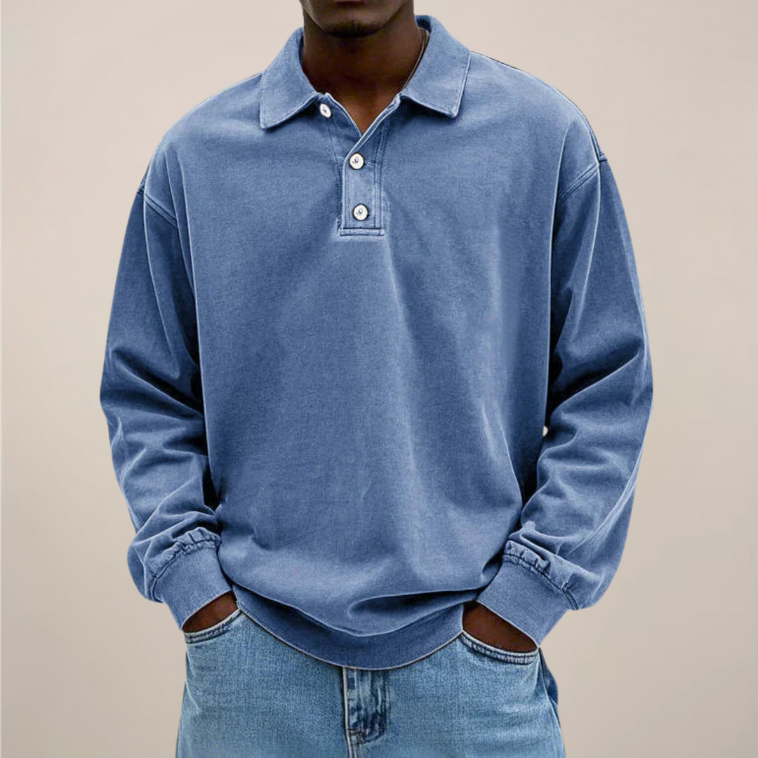 Polo bleu moyen porté par un homme, mains dans les poches d'un jean clair, vue de face. 1