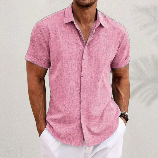 Chemise rose au tissu texturé, portée par un homme en pantalon blanc, avec bracelets au poignet, devant un mur clair. 8