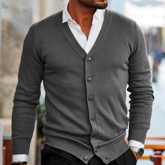Cardigan gris anthracite à col en V et boutons, porté avec une chemise blanche et un pantalon noir en extérieur. 4