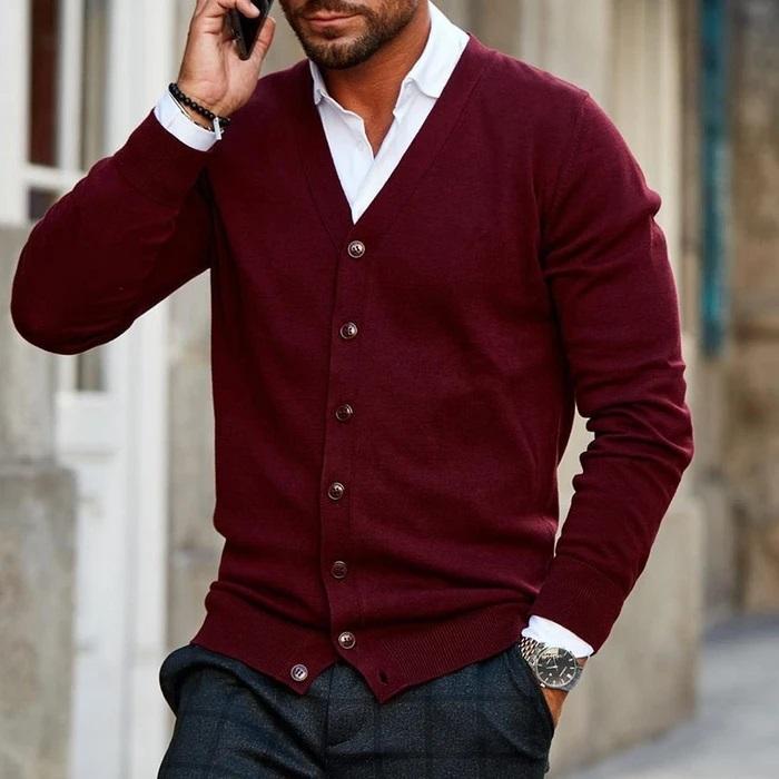 Homme au téléphone portant le cardigan bordeaux boutonné sur une chemise blanche, une main dans la poche d'un pantalon à carreaux gris. 1