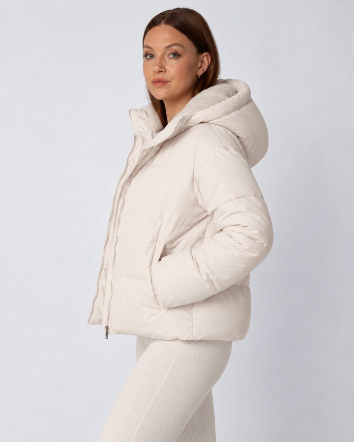 Vue de profil de la veste écru à capuche, mains dans les poches latérales zippées 3