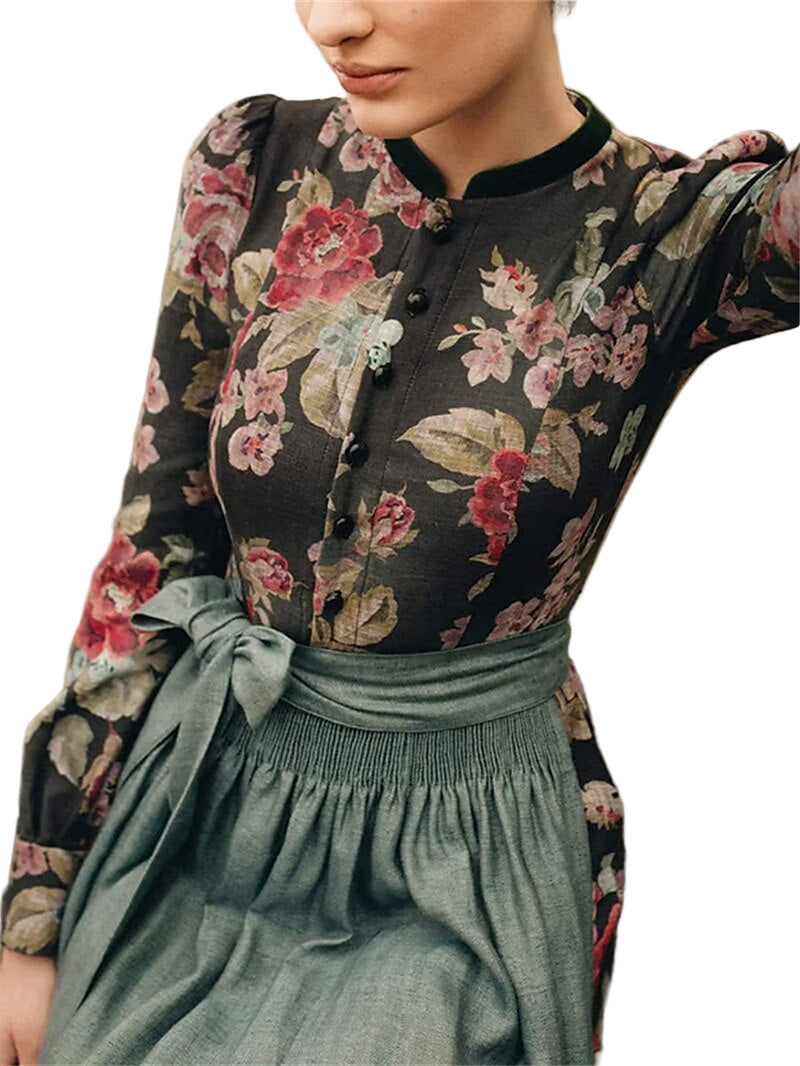 Buste porté par une mannequin : corsage fleuri boutonné, col montant bordé de vert et tablier gris-vert noué à la taille. 2