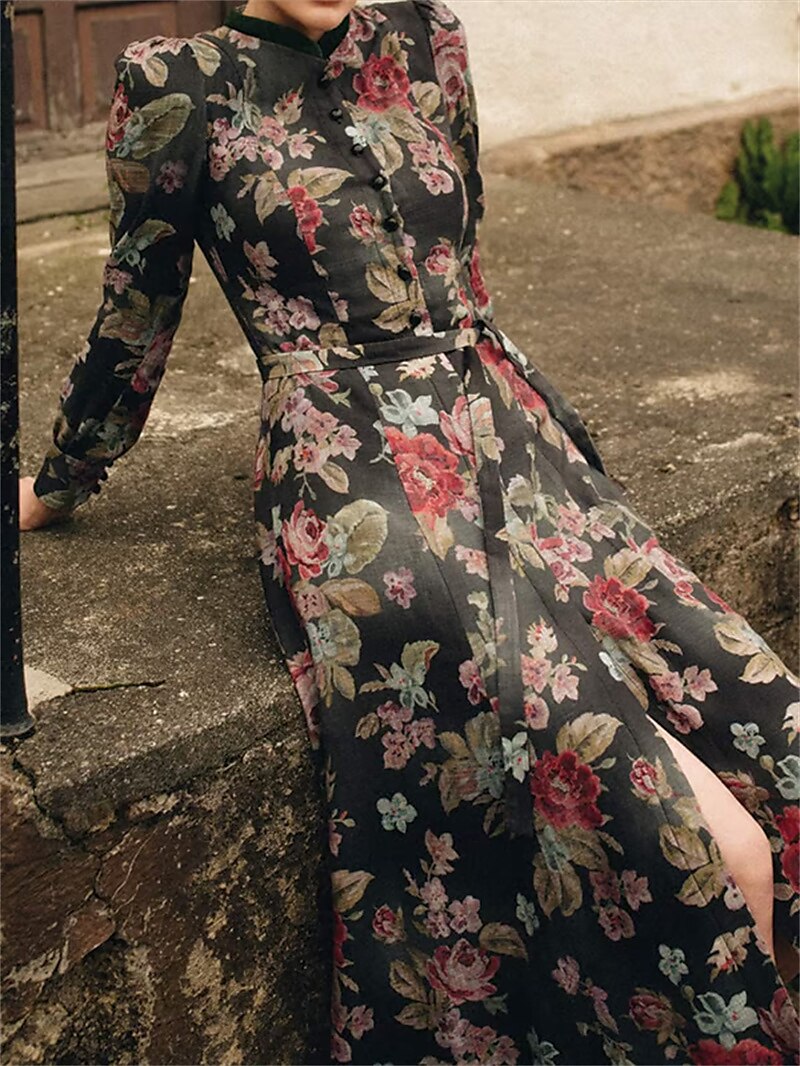 Robe florale longue portée sans tablier, mannequin assise sur un muret de pierre, avec fente sur la jupe et manches longues. 3