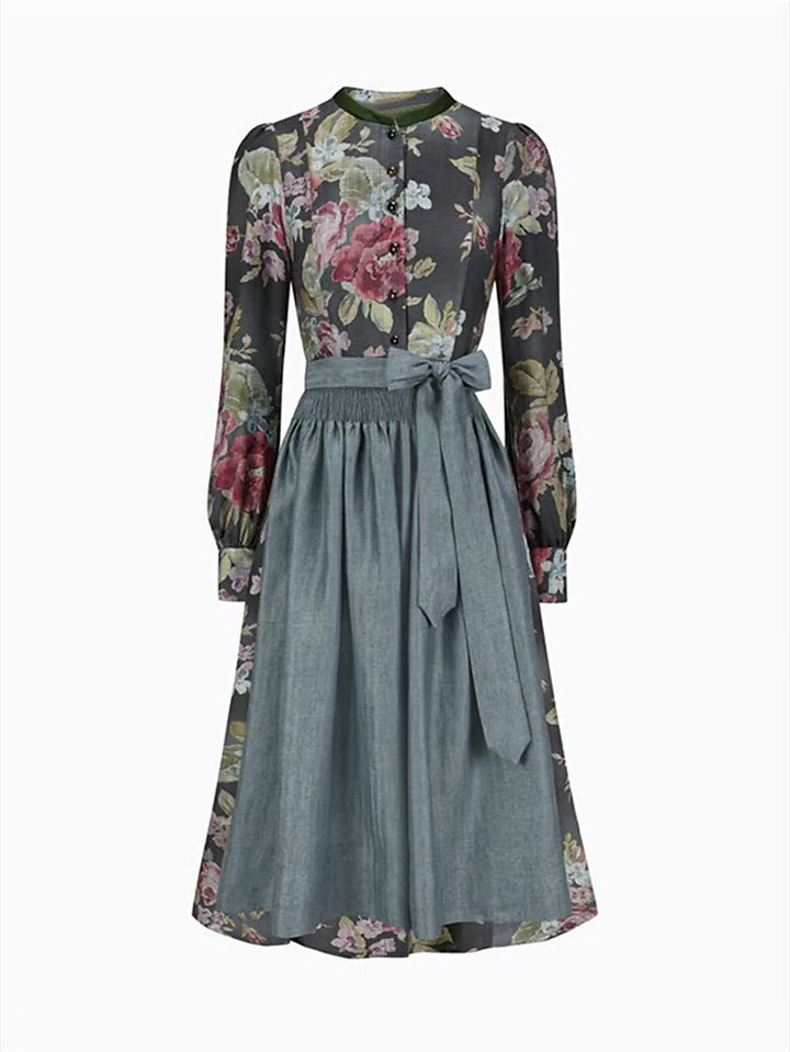 Vue de face de la robe florale à col montant avec tablier gris-bleu noué par un grand nœud, sur fond blanc. 1