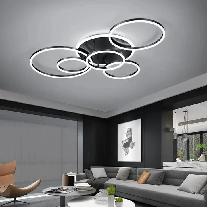 Plafonnier à cinq anneaux noirs lumineux dans un salon moderne gris avec canapé et fauteuil 8