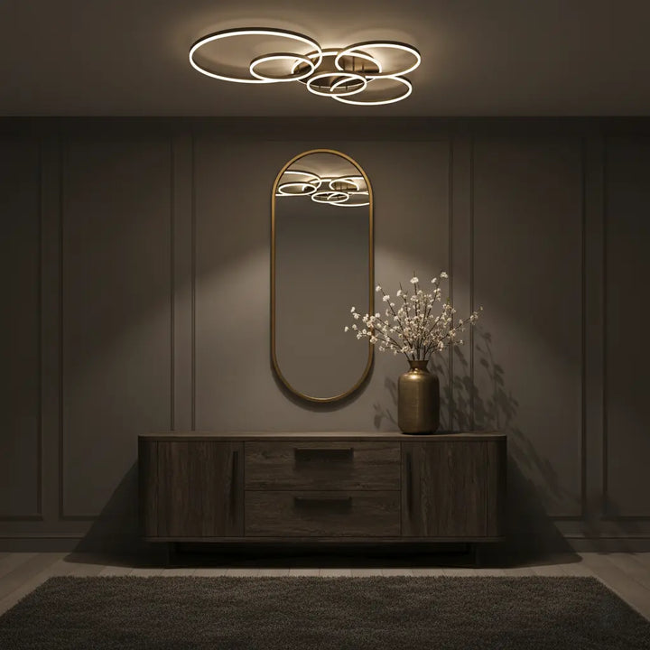 Plafonnier d'anneaux lumineux dans une entrée tamisée, au-dessus d'un miroir ovale et d'un buffet en bois 7