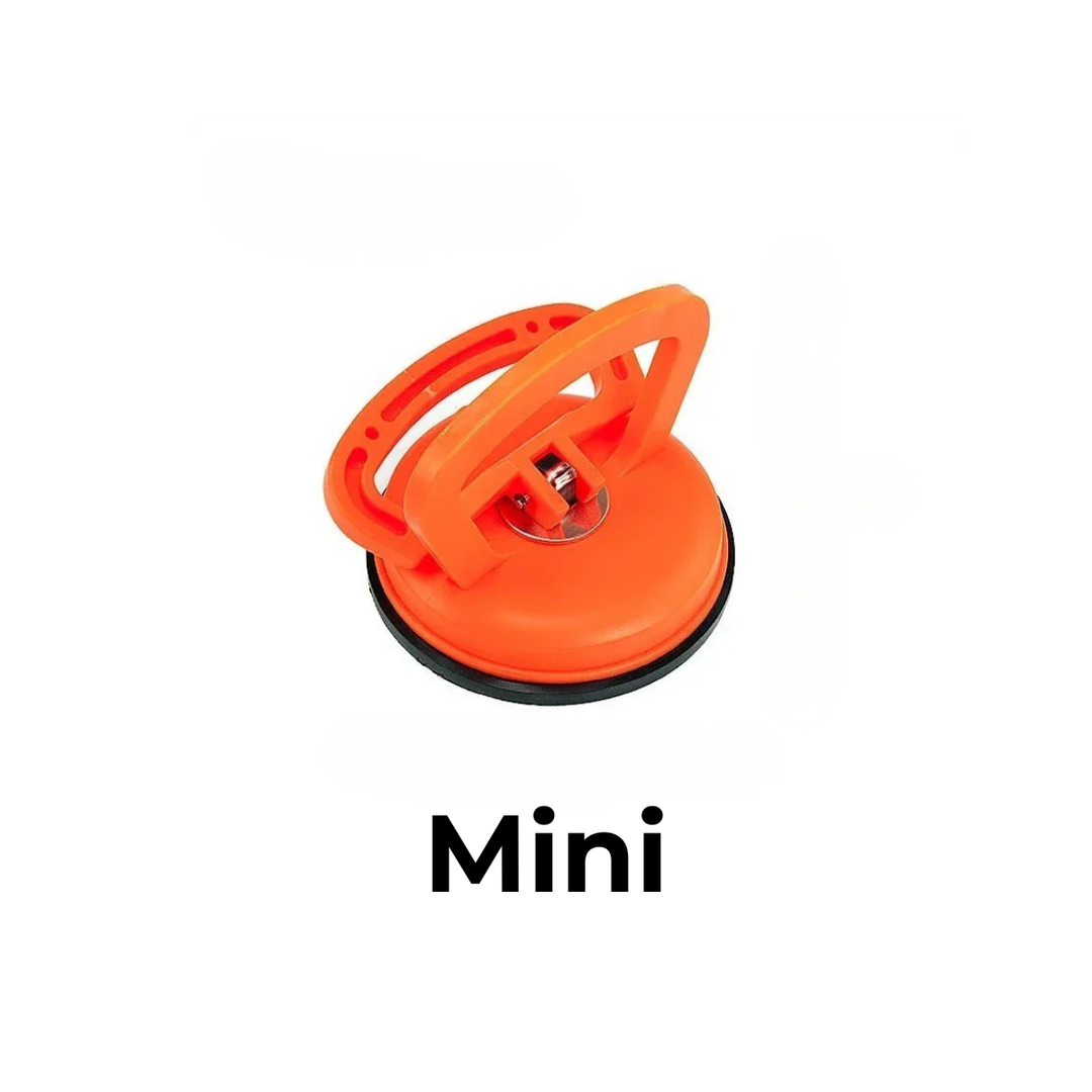 Petite ventouse de débosselage orange avec poignée relevée, vue de dessus sur fond blanc. 6