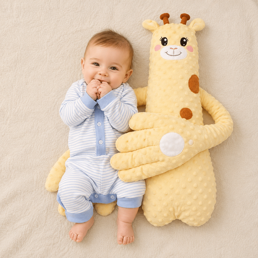 Bébé souriant en grenouillère rayée bleue, allongé à côté d'une grande peluche girafe jaune pâle aux longs bras qui l'enlacent. 2