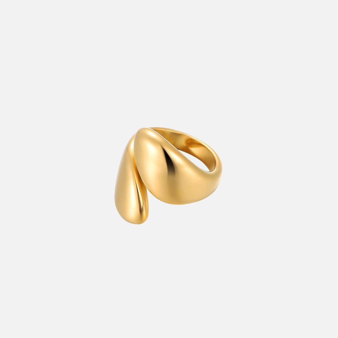 Bague dorée brillante aux deux extrémités en forme de goutte qui se chevauchent, vue de trois quarts sur fond gris clair. 1
