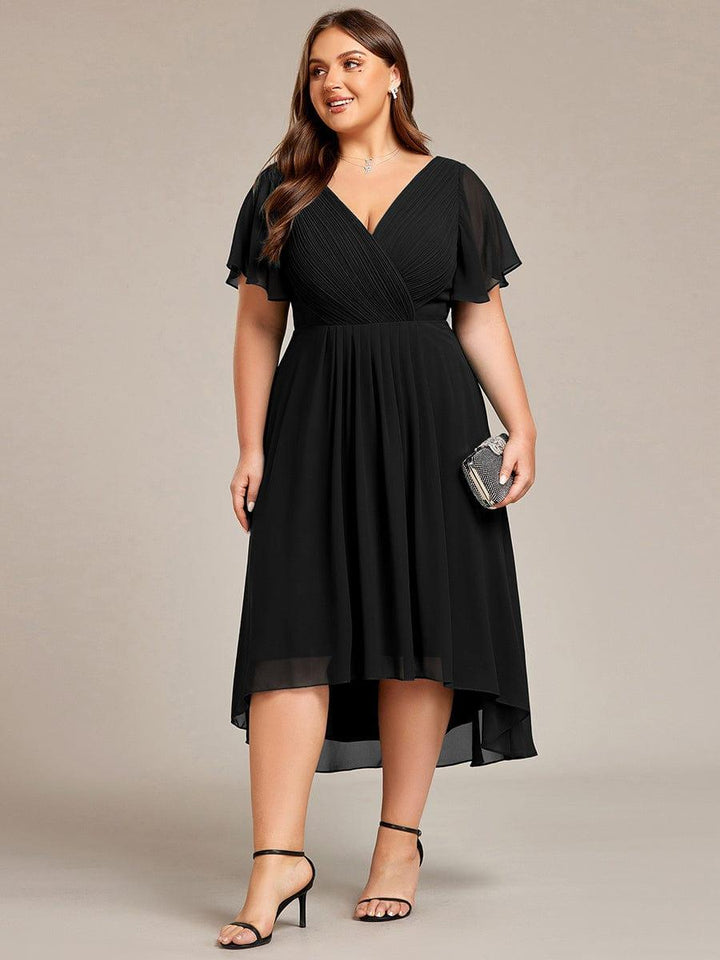 Robe noire grande taille portée de face, mannequin tenant une pochette scintillante, ourlet asymétrique plus long derrière. 30