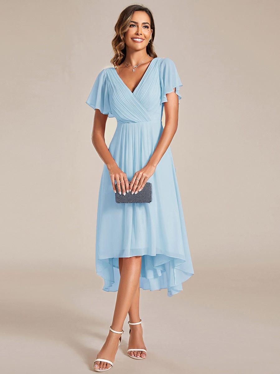 Robe bleu ciel portée de face, mannequin tenant une pochette, jupe en mousseline plus longue à l'arrière 87