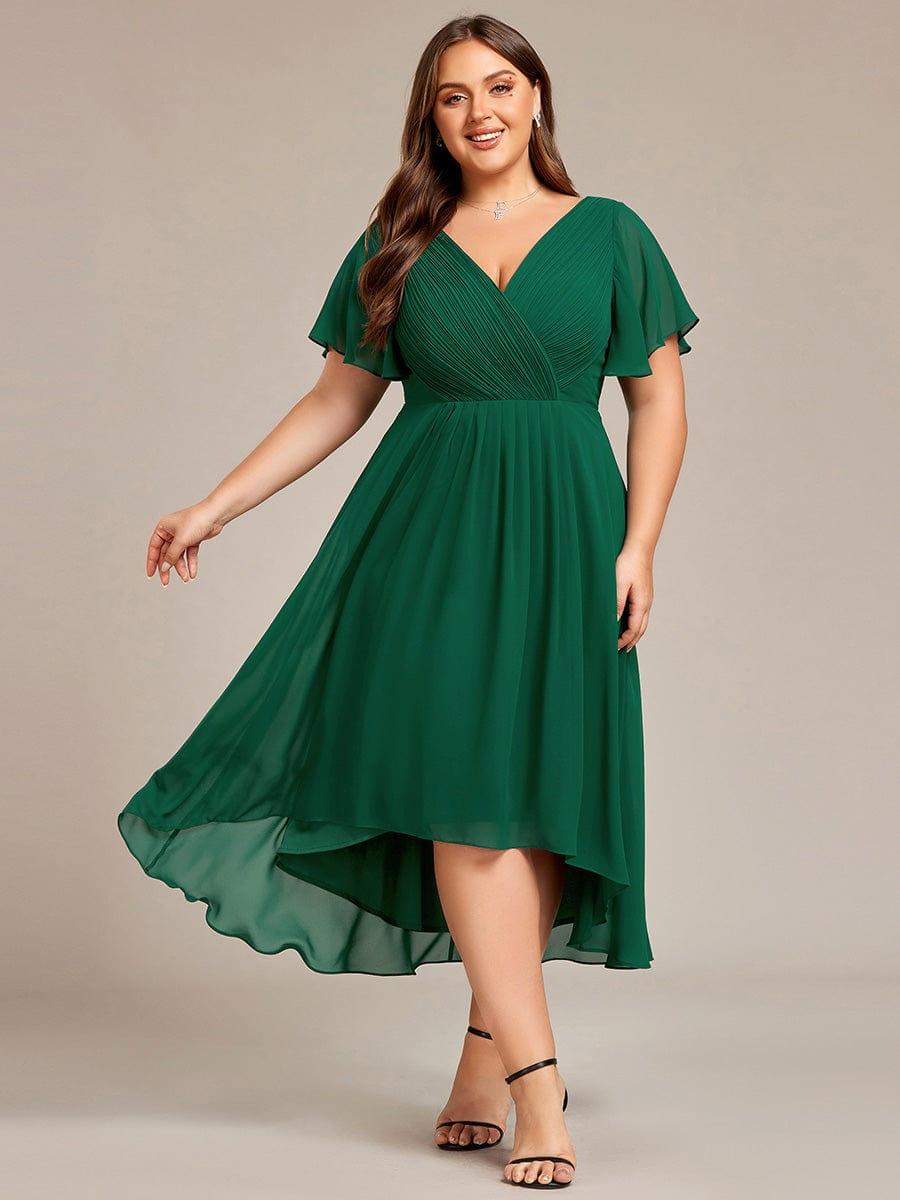 Robe vert foncé grande taille portée de face par une mannequin, jupe en mousseline à ourlet asymétrique en mouvement. 36