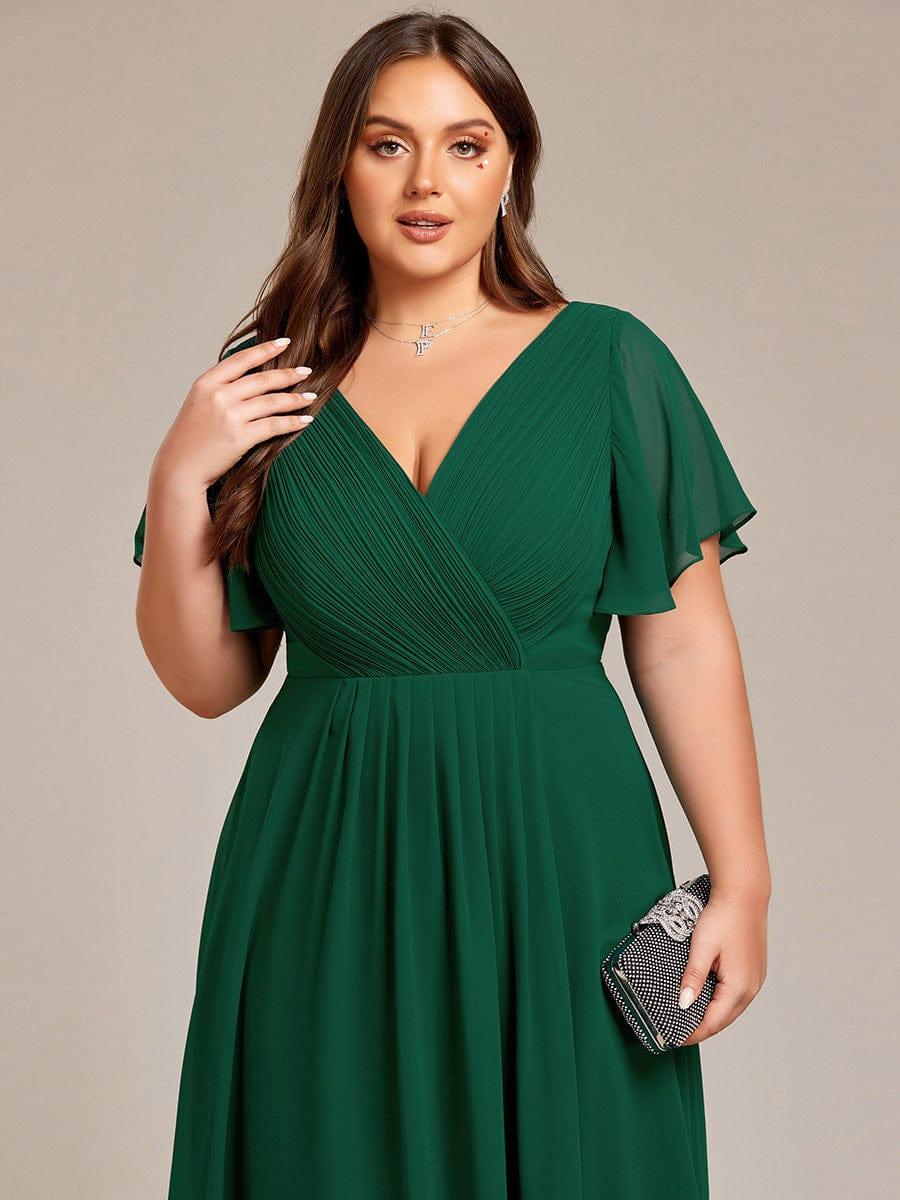 Gros plan sur le buste de la robe vert foncé, corsage plissé croisé, manches volantées et pochette scintillante. 38