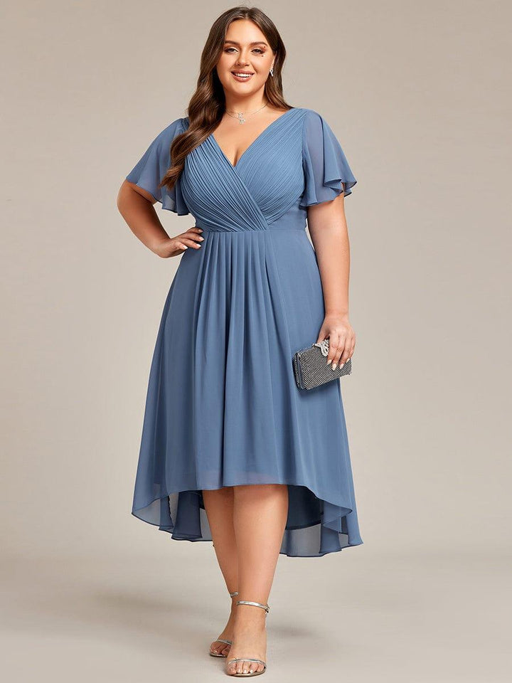 Mannequin grande taille en robe bleu grisé, main sur la hanche, pochette scintillante à la main, sandales argentées, vue de face. 44