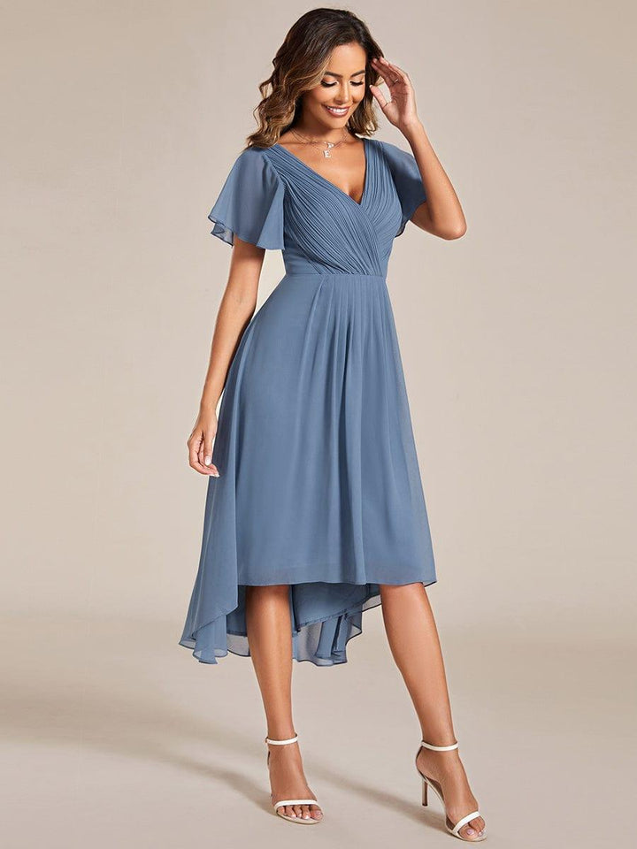 Robe bleu grisé portée de trois quarts, mannequin souriante main au visage, jupe fluide plus longue sur le côté. 9