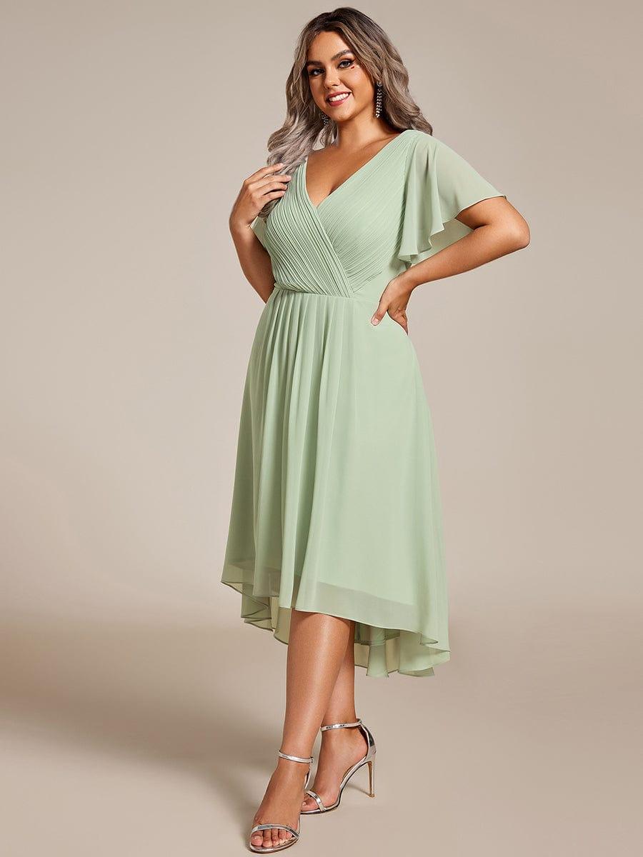Robe vert sauge portée par une mannequin, vue de trois quarts, main sur la hanche, jupe asymétrique en mousseline plissée 81