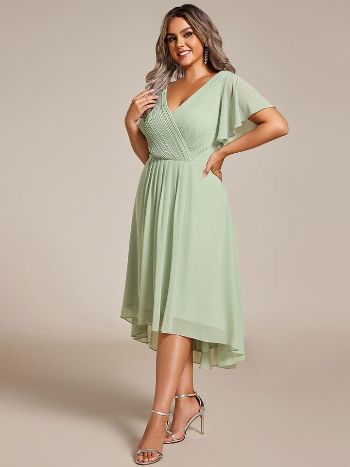 Robe vert sauge portée par une mannequin, vue de trois quarts, main sur la hanche, jupe asymétrique en mousseline plissée 81