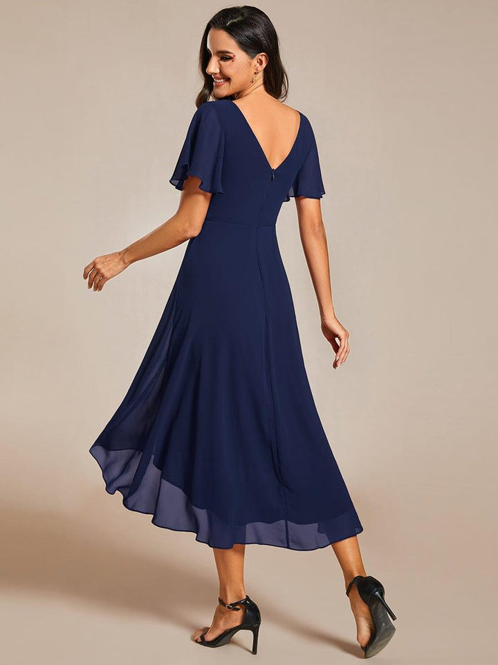 Vue de dos de la robe bleu marine, décolleté en V dans le dos, fermeture zippée et manches volantées. 2