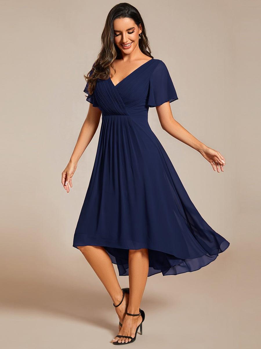 Robe bleu marine en mousseline portée avec des sandales noires, mannequin en mouvement, jupe asymétrique et manches courtes évasées. 52