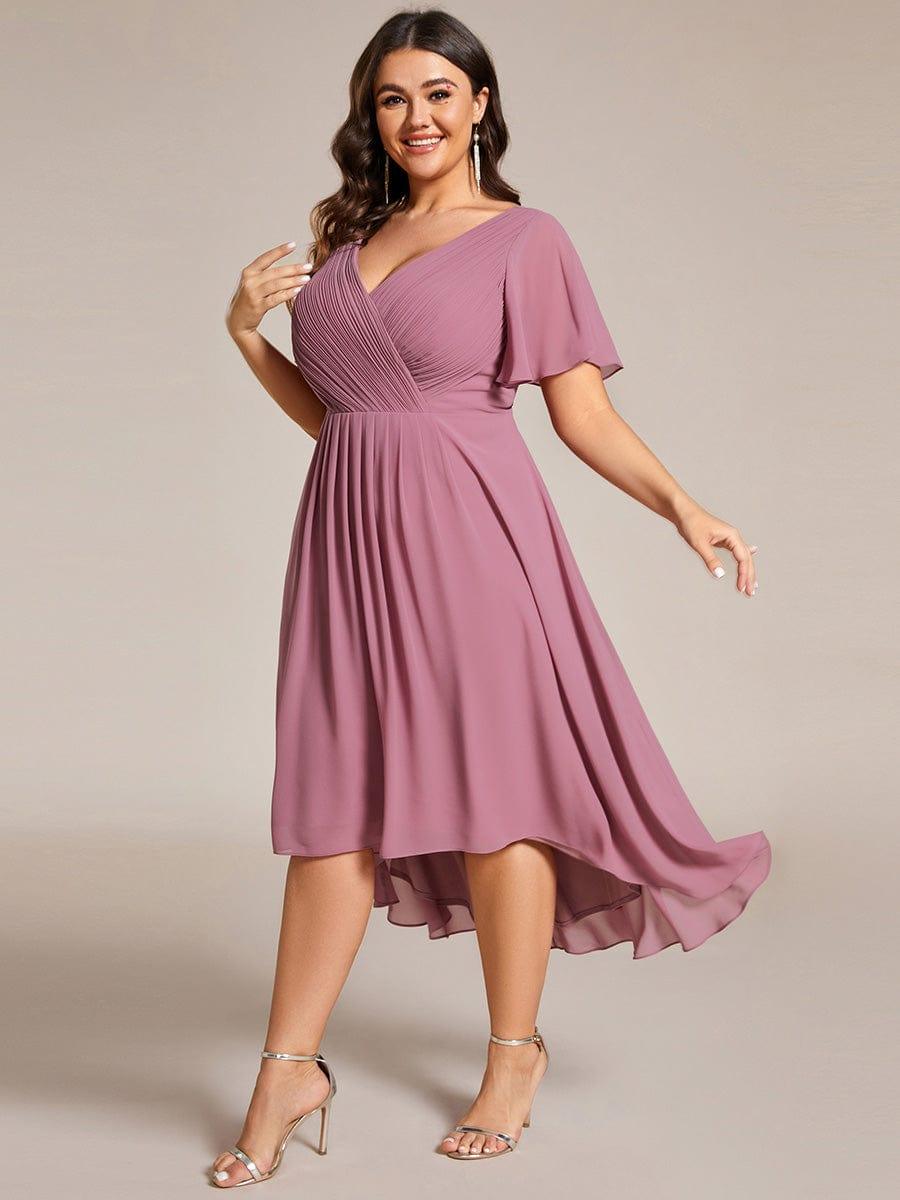 Robe mauve rosé en grande taille vue de trois quarts, la mannequin en mouvement, jupe fluide asymétrique et sandales dorées. 67