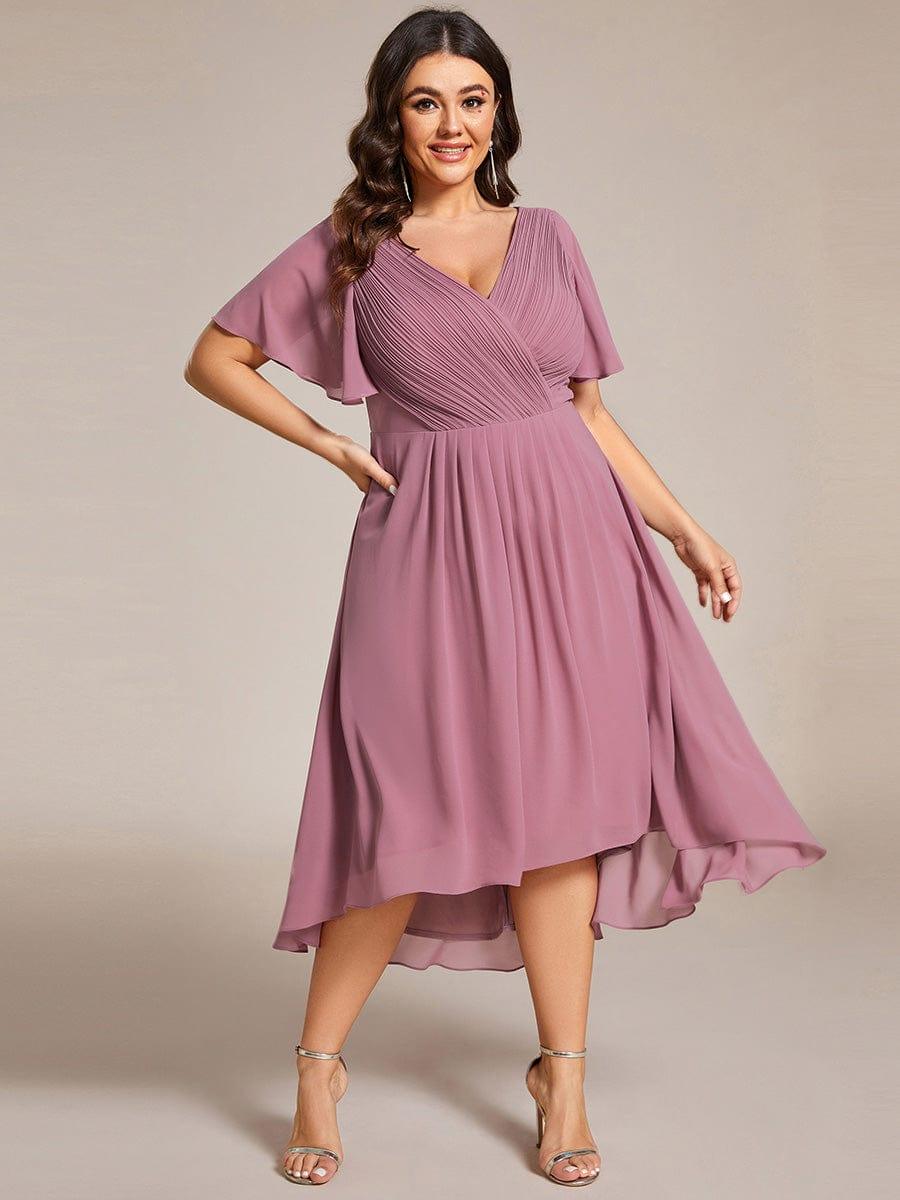 Robe mauve rosé portée par une mannequin en grande taille, une main sur la hanche, jupe évasée à ourlet asymétrique. 66
