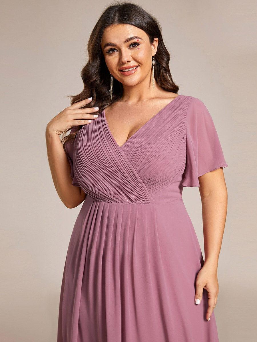 Gros plan sur le buste plissé croisé et le col en V de la robe mauve rosé, porté par une mannequin en grande taille. 65