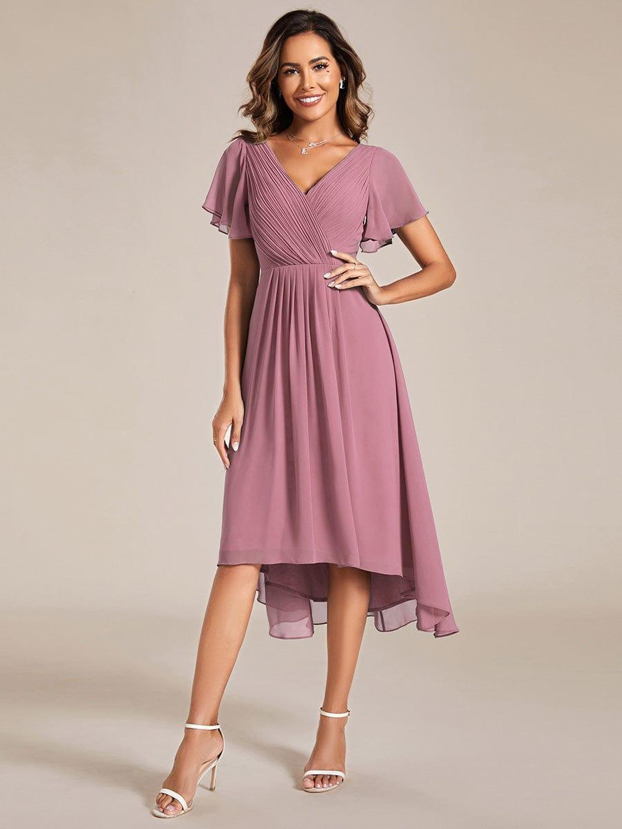 Robe rose mauve en mousseline portée avec des sandales blanches, mannequin souriante main sur la hanche, jupe asymétrique mi-longue. 58