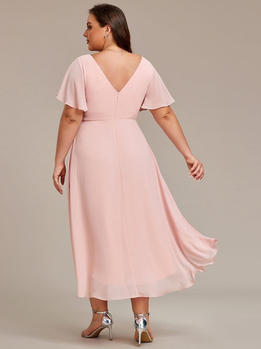 Robe rose pâle grande taille vue de dos, décolleté en V, fermeture éclair centrale et jupe asymétrique qui flotte. 32