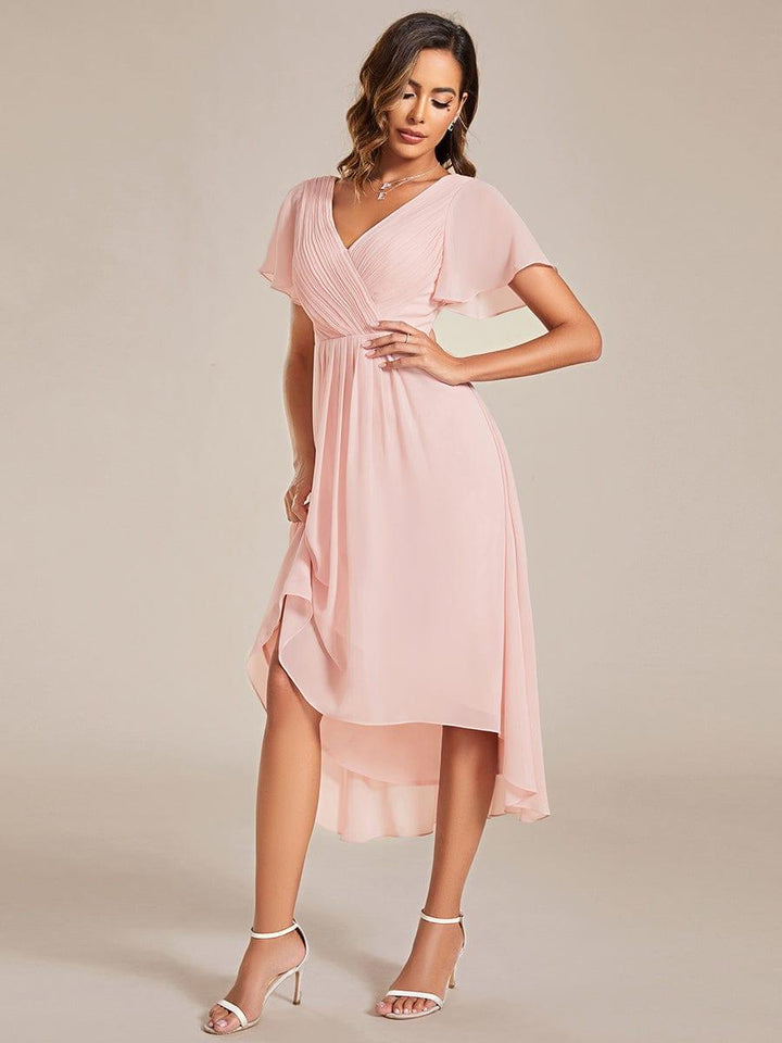 Robe rose pâle portée de trois quarts, mannequin soulevant légèrement la jupe pour montrer l'ourlet asymétrique. 19
