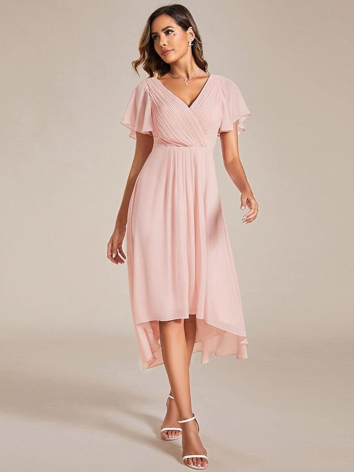 Robe rose pâle portée en marchant, jupe fluide en mousseline plus longue à l'arrière, manches volantées et sandales blanches. 20