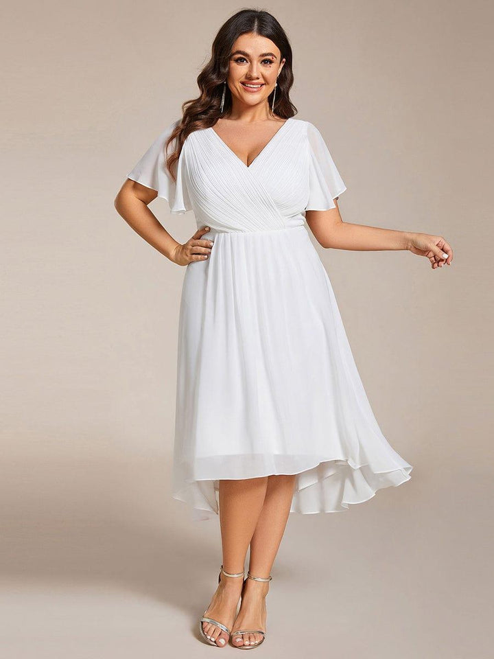 Robe blanche portée de face par une mannequin en grande taille, main sur la hanche, jupe fluide à ourlet asymétrique. 73