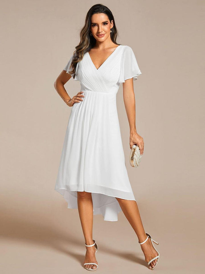 Robe blanche portée par une mannequin, une main sur la hanche et une pochette perlée dans l'autre, ourlet asymétrique. 71