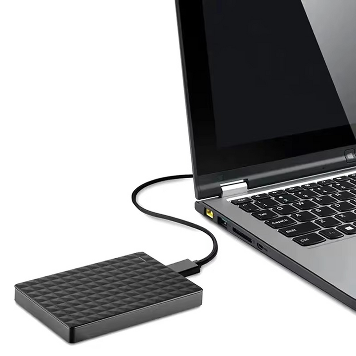 Disque dur noir relié par un câble à un port USB sur le côté d'un ordinateur portable ouvert, fond blanc. 4