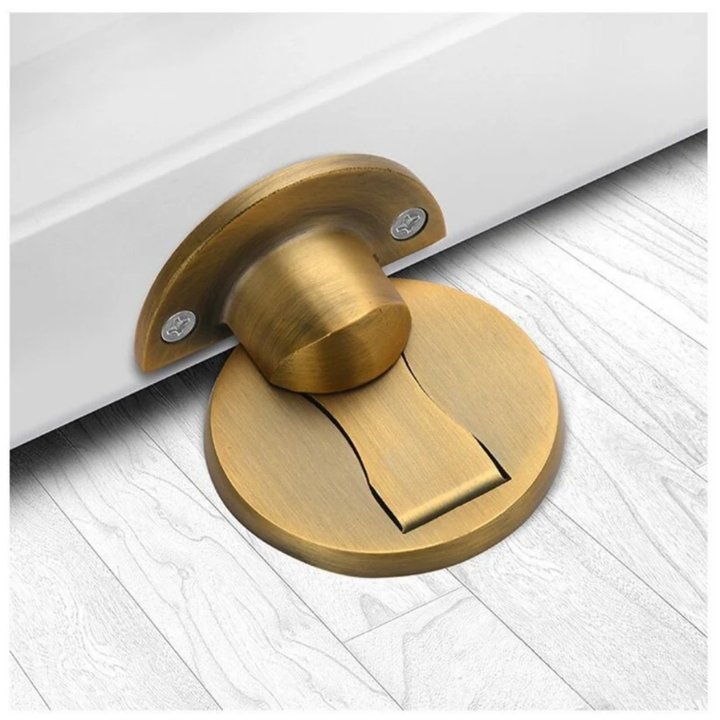 Version laiton antique brossé, butée magnétique posée sur parquet clair avec son support demi-lune fixé à la porte. 6