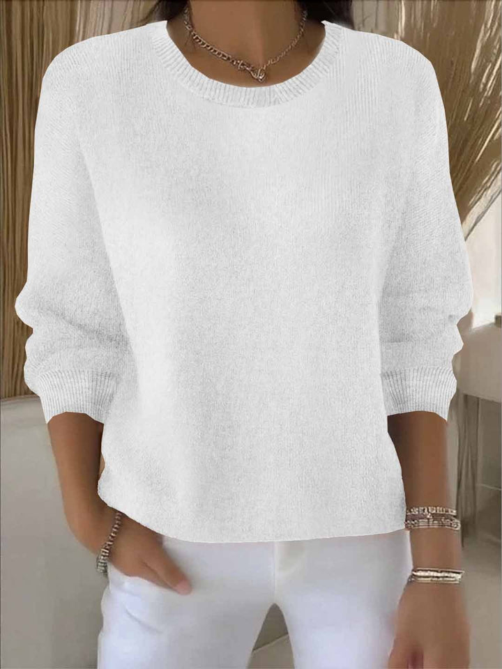 Pull blanc à col rond et poignets côtelés, porté avec un pantalon blanc et un collier 3