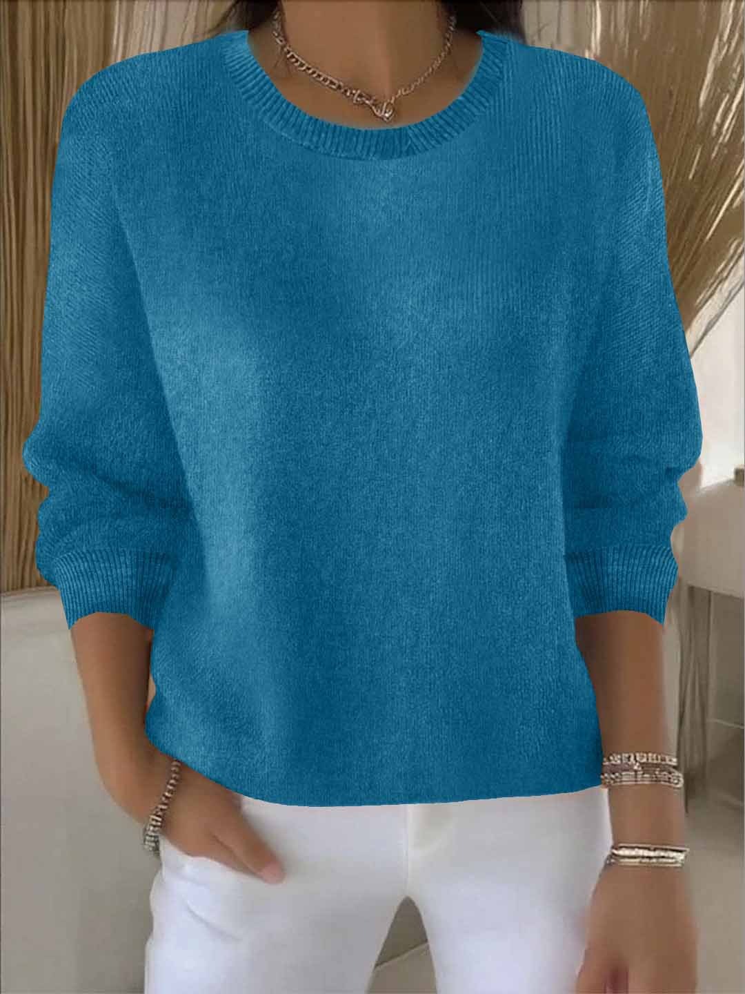 Pull bleu canard à col rond et poignets côtelés, porté avec un pantalon blanc 12