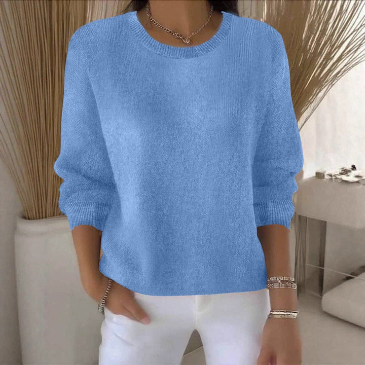 Pull bleu moyen à col rond, porté avec un pantalon blanc devant des herbes séchées 13