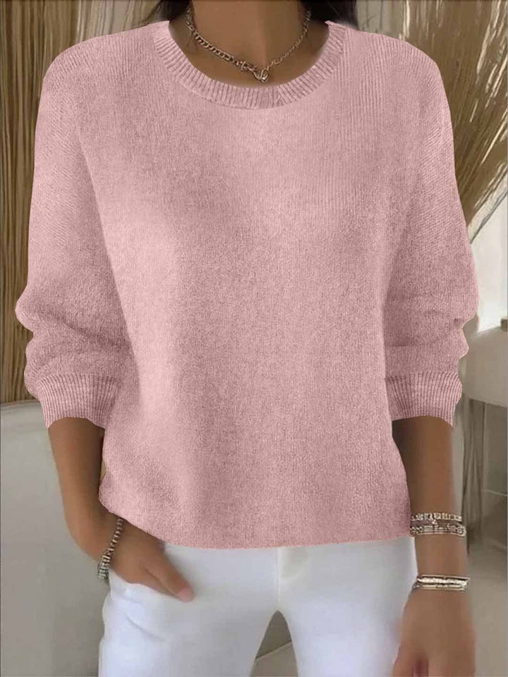 Pull rose pâle à col rond et poignets côtelés, porté avec un pantalon blanc 2