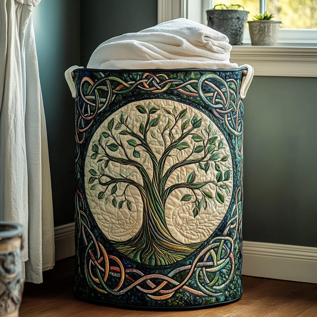 Panier cylindrique matelassé orné d'un arbre de vie brodé sur fond crème et d'entrelacs celtiques, rempli de serviettes blanches près d'une fenêtre. 1