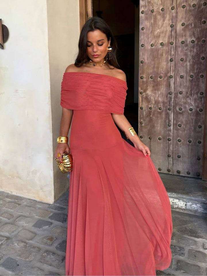 Robe corail à épaules dénudées, jupe légère soulevée d'une main, buste plissé en maille 8