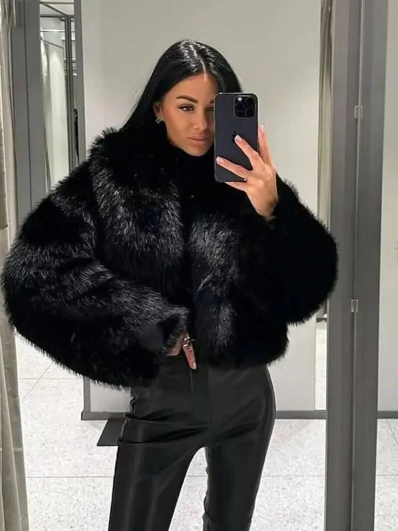 Femme se prenant en photo dans un miroir avec le manteau noir en fausse fourrure et un pantalon en cuir noir 11